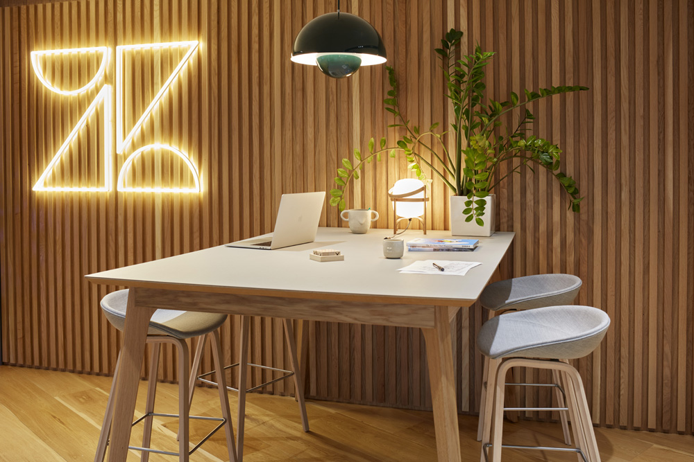 A workstation in Zendesk, London containing a laptop, light and green plant